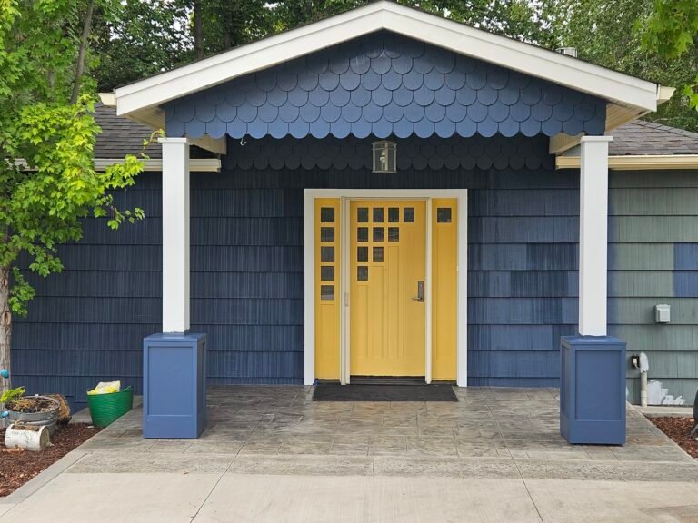 New construction home exterior painting with blue siding, white trim, and yellow front door